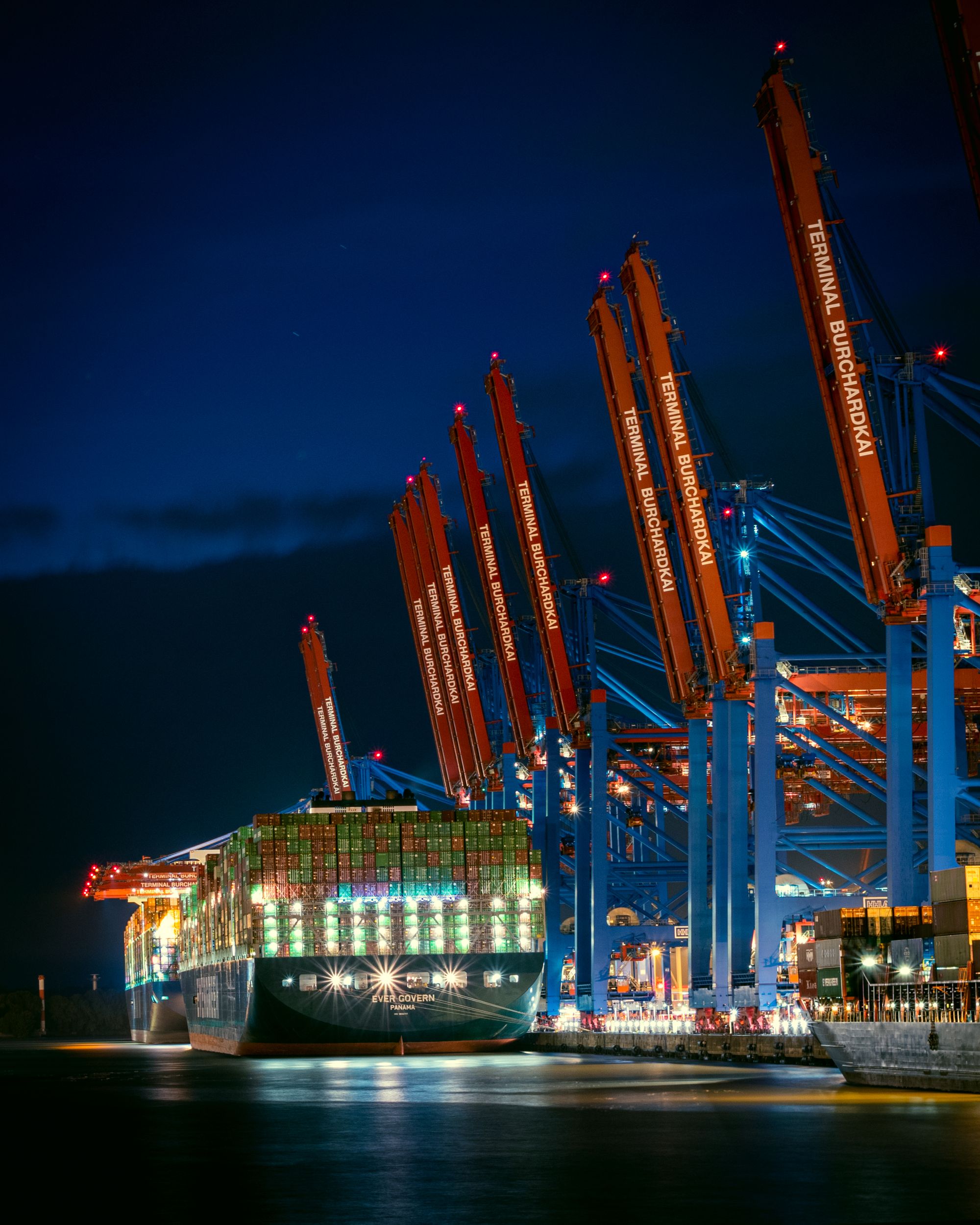 Container port cranes illuminated at dusk